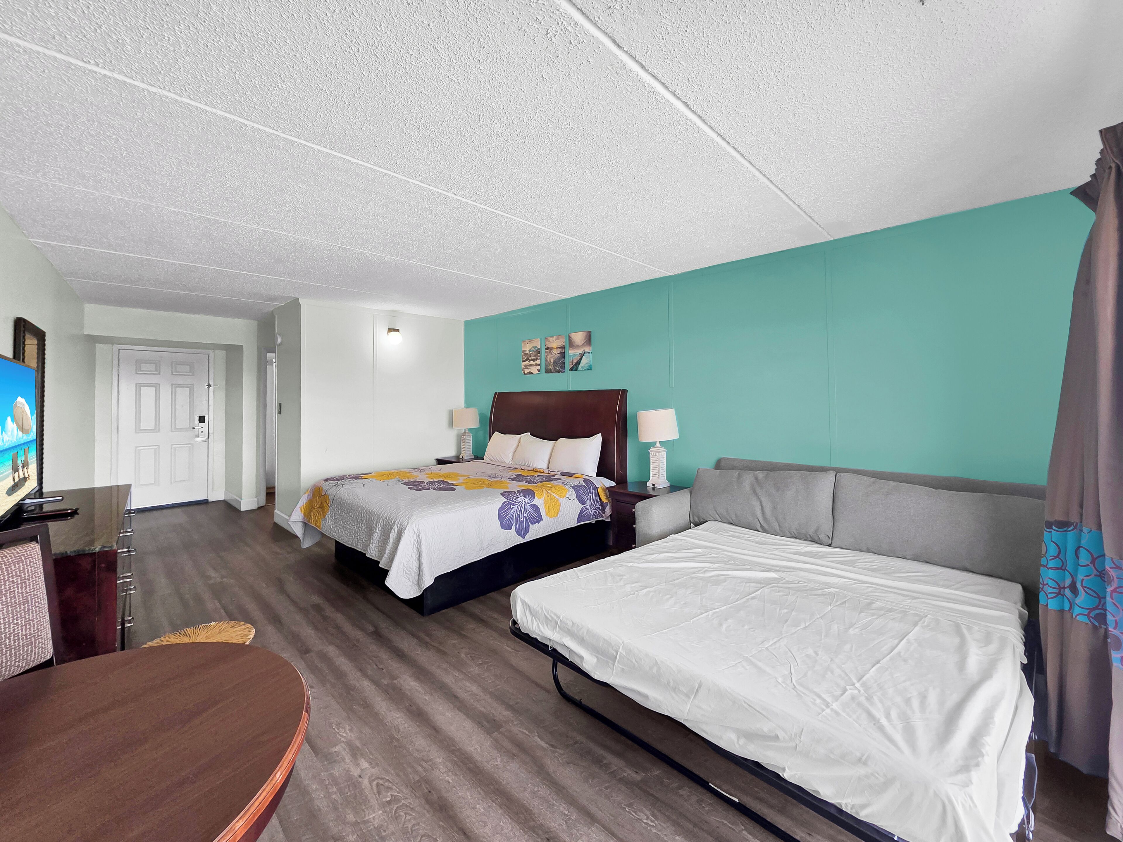 Habitación de hotel con dos camas, un escritorio y una televisión.