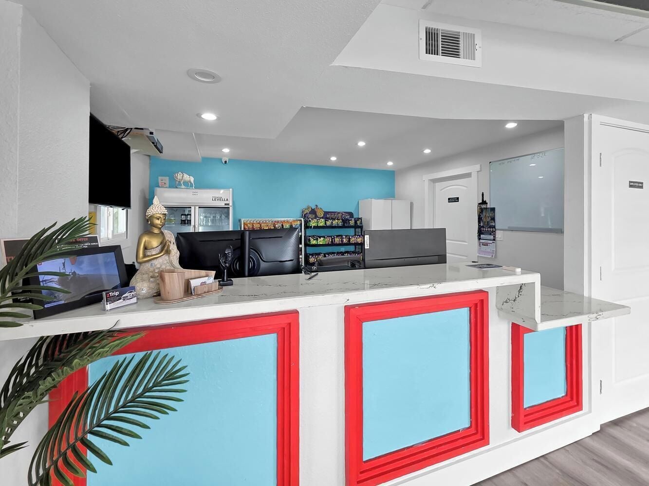 A reception desk with a blue and red color scheme, a television, and a statue.