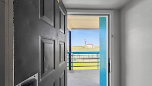 A doorway leading to an outdoor area with a blue fence and a red structure in the distance. - Crystal Palace Resort (Port Bolivar)