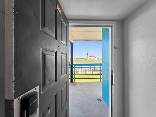 A doorway leading to an outdoor area with a blue fence and a red structure in the distance. - Crystal Palace Resort (Port Bolivar)