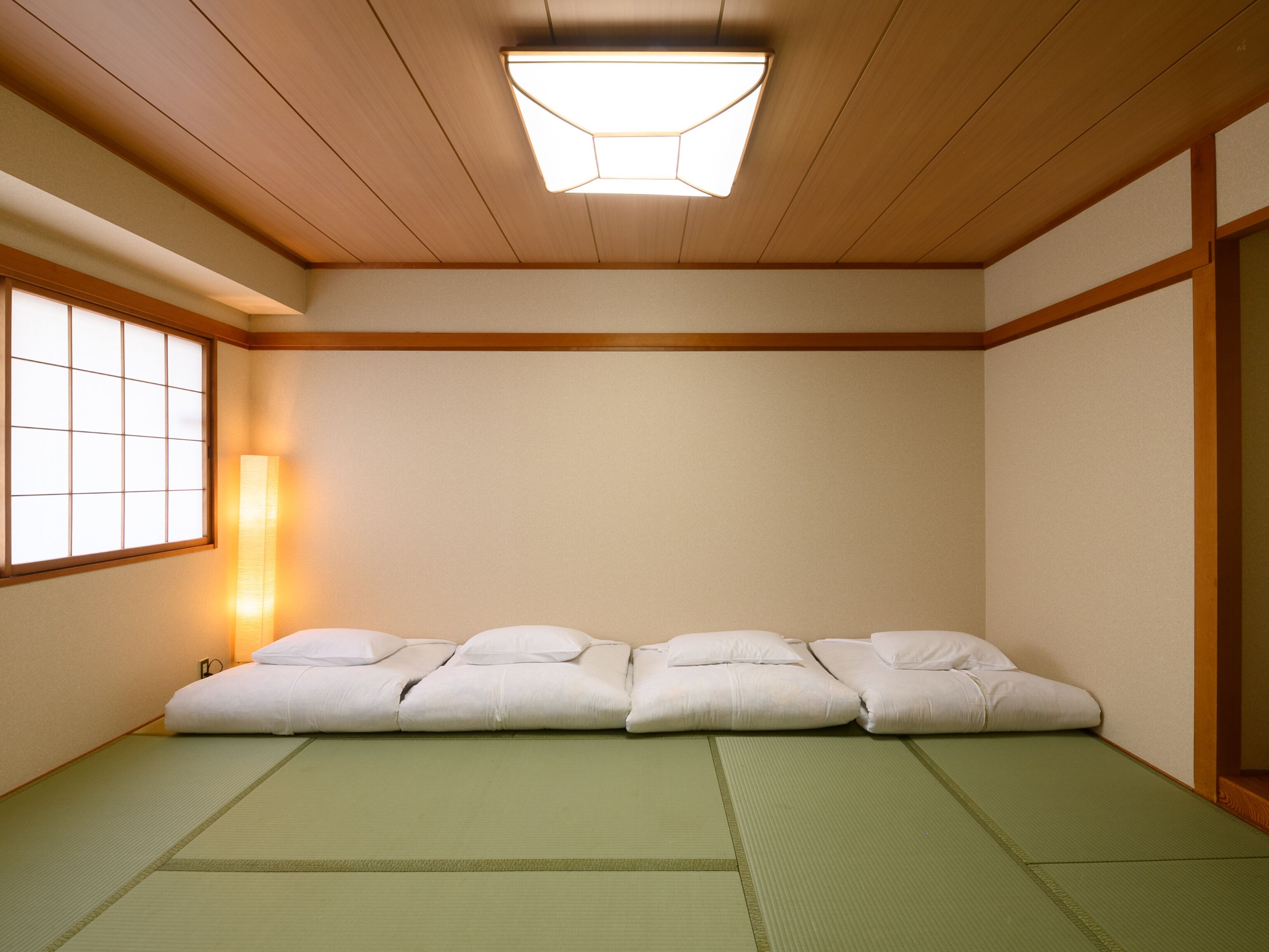 A traditional Japanese room with tatami mats, a low wooden ceiling, and a shoji screen.