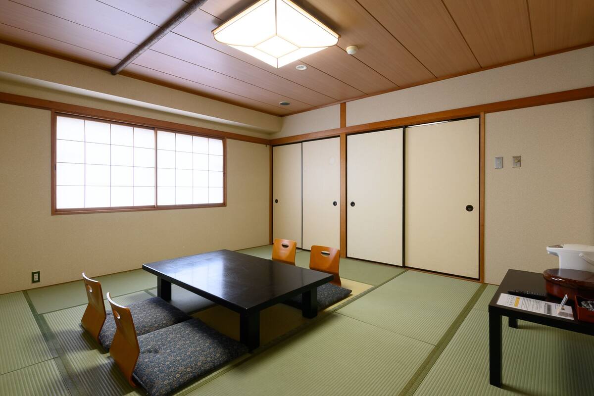 Una habitación japonesa tradicional con suelo de tatami, una mesa baja y puertas correderas.