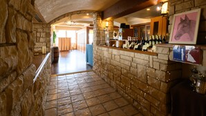 A stone-walled bar area with a tiled floor, wine bottles, and a framed horse picture. - Sabae City Hotel (Sabae)