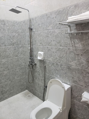 A modern bathroom with a shower, toilet, and marble tiles. - Hancol Hotel (Dodoma)