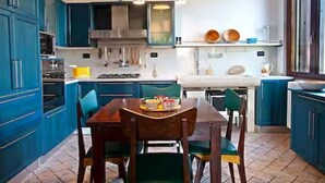 Una cocina con armarios azules, una mesa de comedor con sillas y una lámpara colgante.