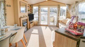 Ein gemütliches Zimmer mit Fernseher, Esstisch, Stühlen und einer Couch.