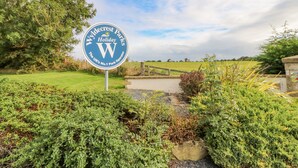 Ein Schild für Wyldecrest Holiday Parks mit freiem Blick auf die umliegende Grünfläche und einem Weg, der zum Park führt.
