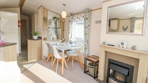Ein modernes Wohnzimmer mit Kamin, einem Essbereich mit Tisch und Stühlen sowie einem großen Spiegel an der Wand.