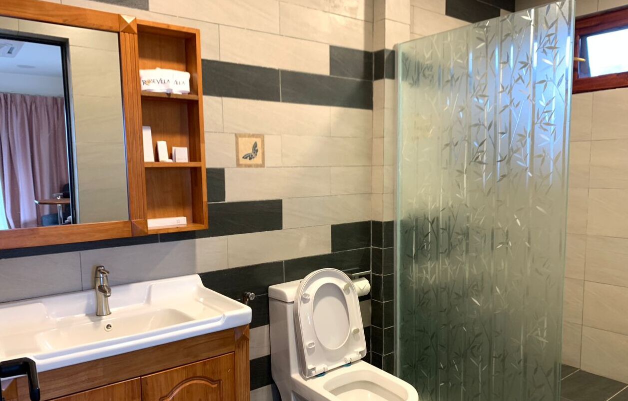 Et badeværelse med en hvid vask, toilet og en brusekabine i glas.