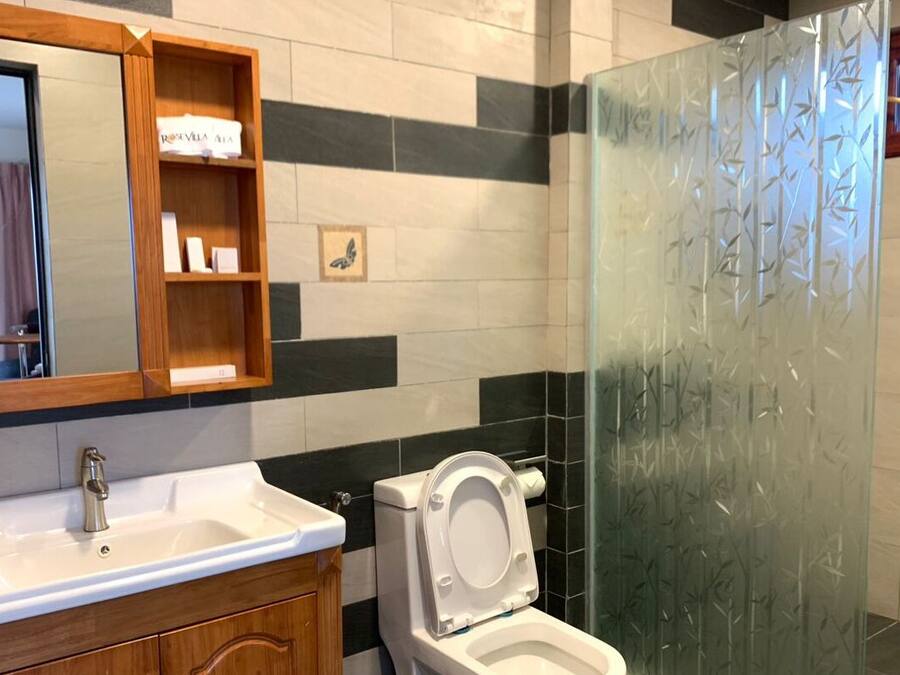 Et badeværelse med en hvid vask, toilet og en brusekabine i glas.