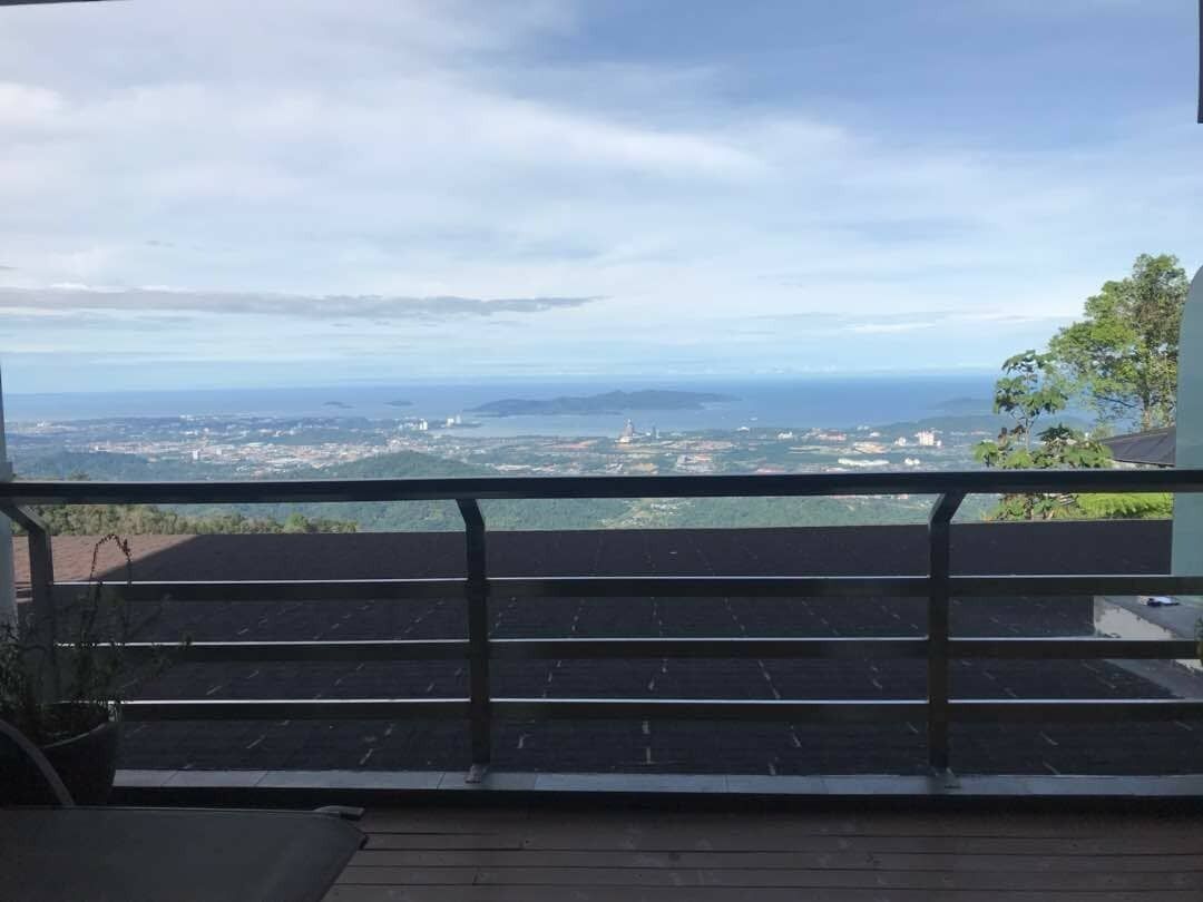A balcony with a view of a coastal landscape, including a cityscape and distant islands.
