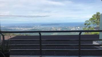 A balcony with a view of a coastal landscape, including a cityscape and distant islands.
