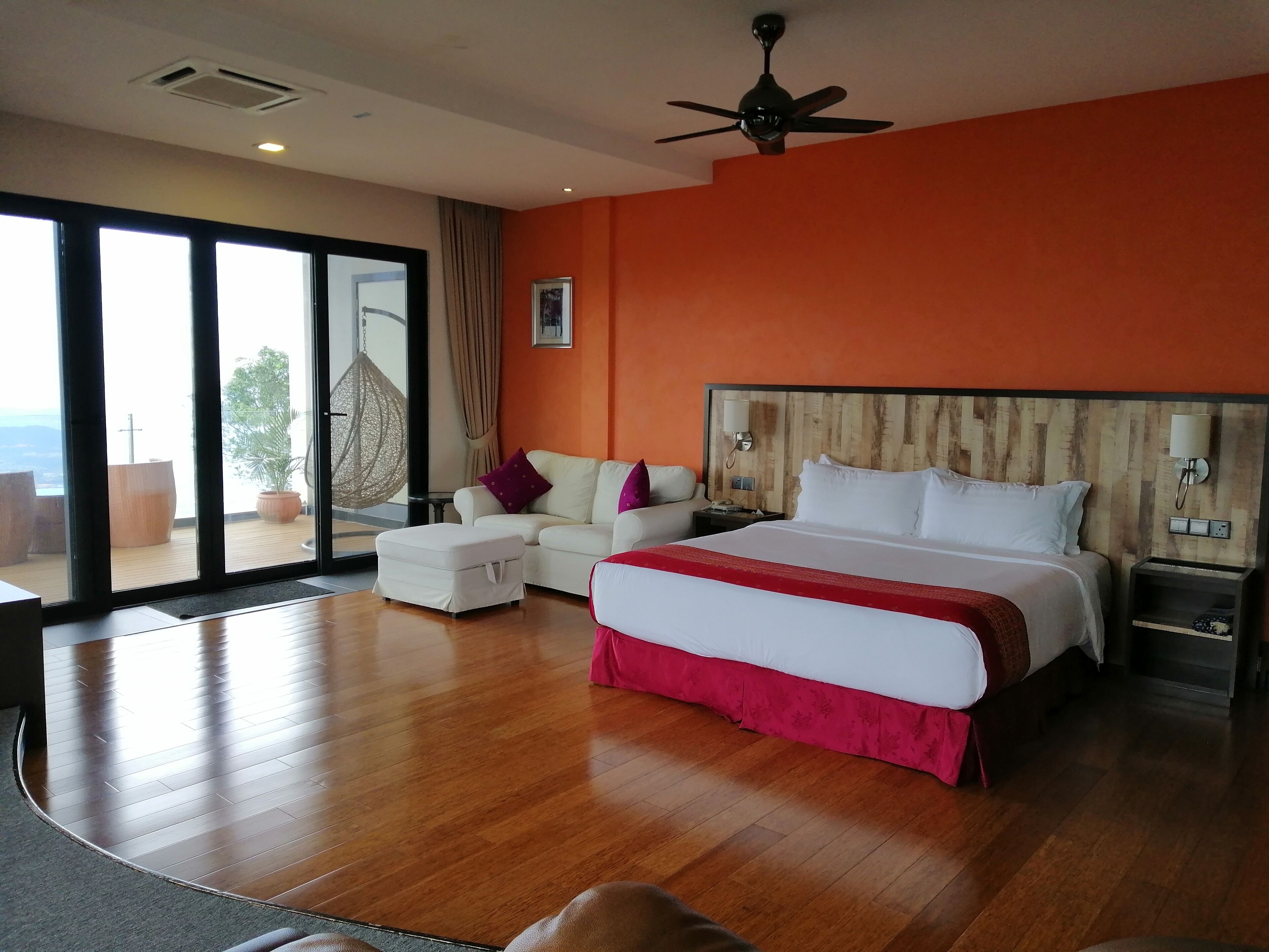 Habitación de hotel con una cama grande, un sofá, una mesita de noche y vistas al exterior.