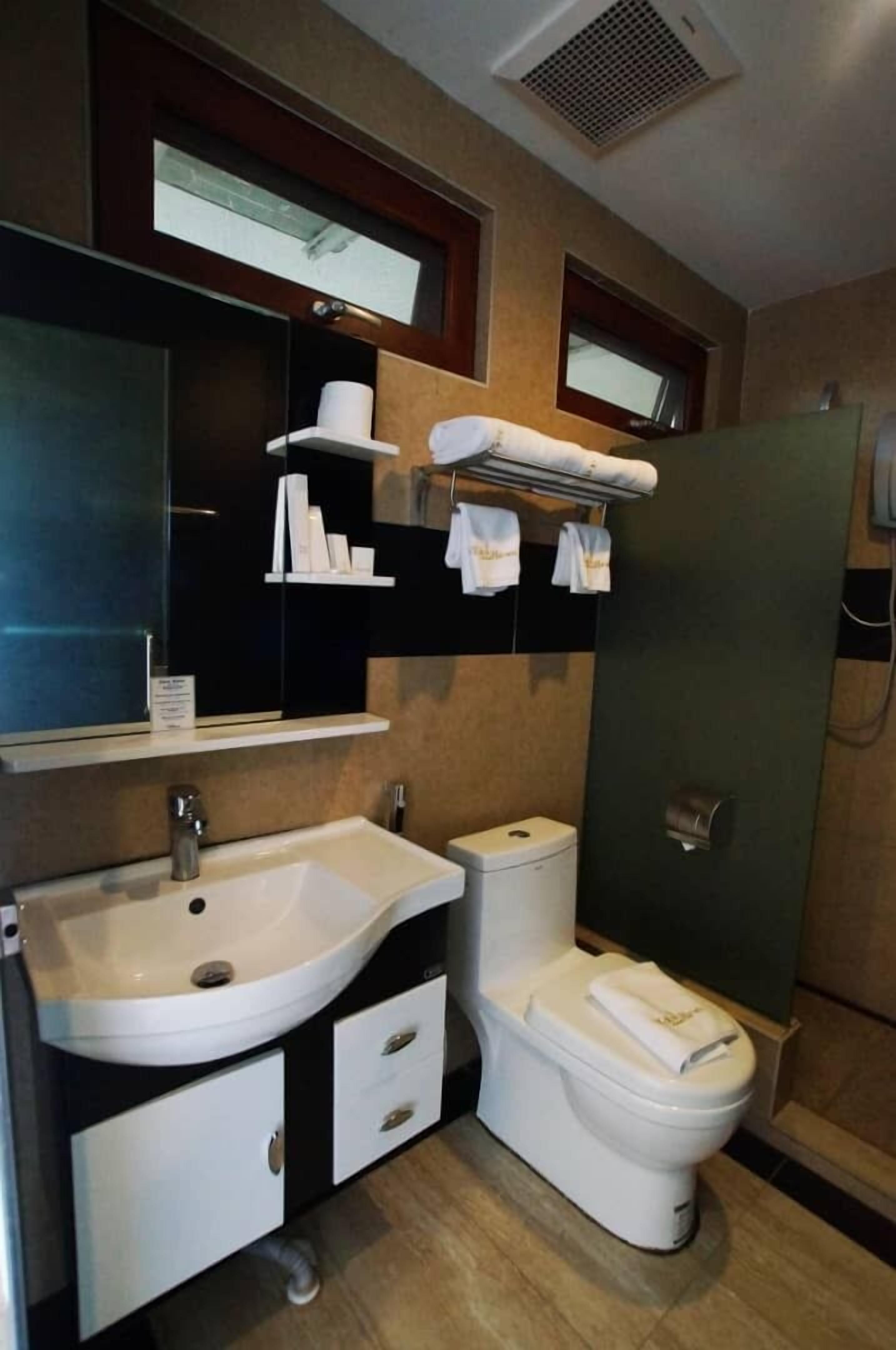 A modern bathroom with a sink, toilet, and shower. There are towel racks above the toilet and a mirror above the sink.