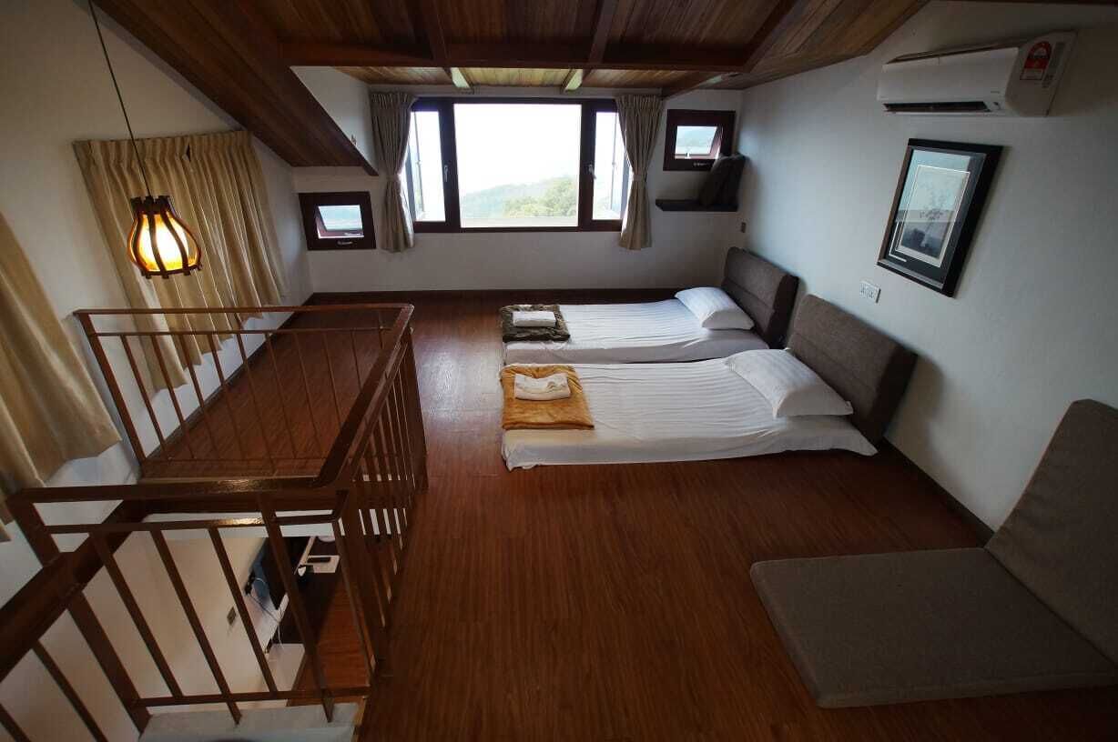 A room with two beds, a wooden staircase, and a window with curtains.