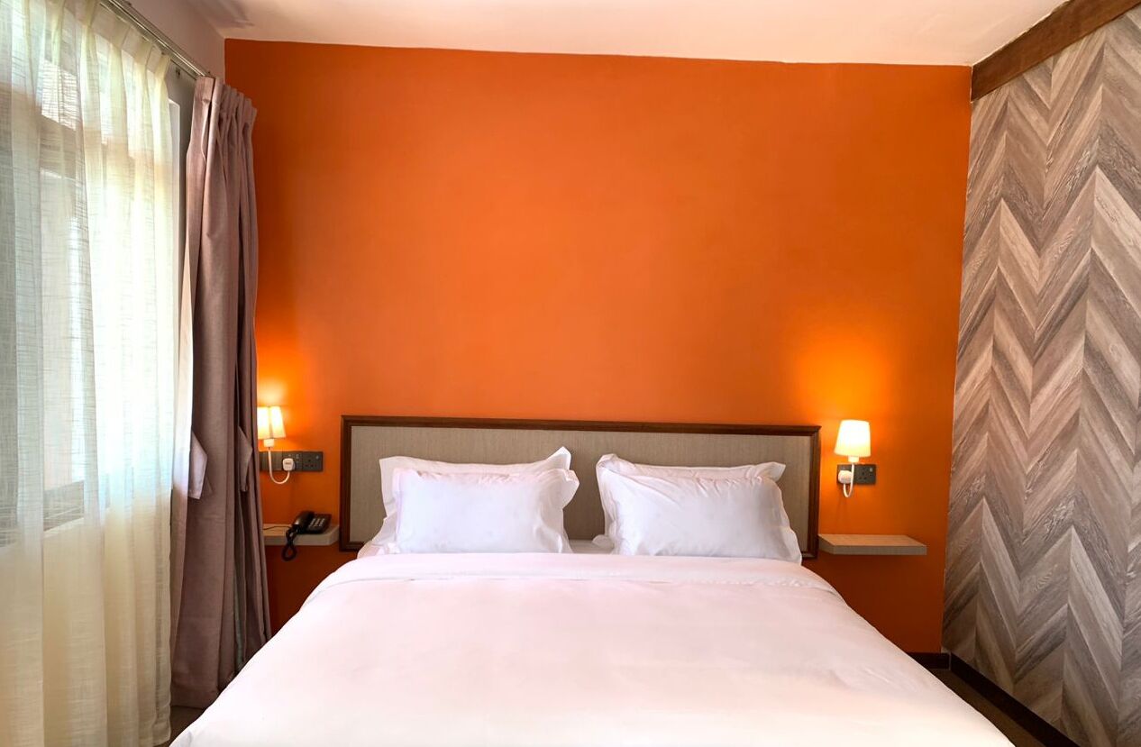 A hotel room with a large bed, two bedside lamps, a telephone, and a mirror on the wall.