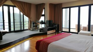 A hotel room with a large bed, a desk with a TV, and a balcony with a view. - Kokol Haven Resort (Kota Kinabalu)