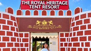 Une personne se tient devant l’entrée du Royal Heritage Tent Resort, avec une enseigne au-dessus.