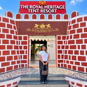 A person standing in front of The Royal Heritage Tent Resort entrance with a sign above. - The Royal Heritage Tent Resort - Statue Of Unity (Garudeshwar)