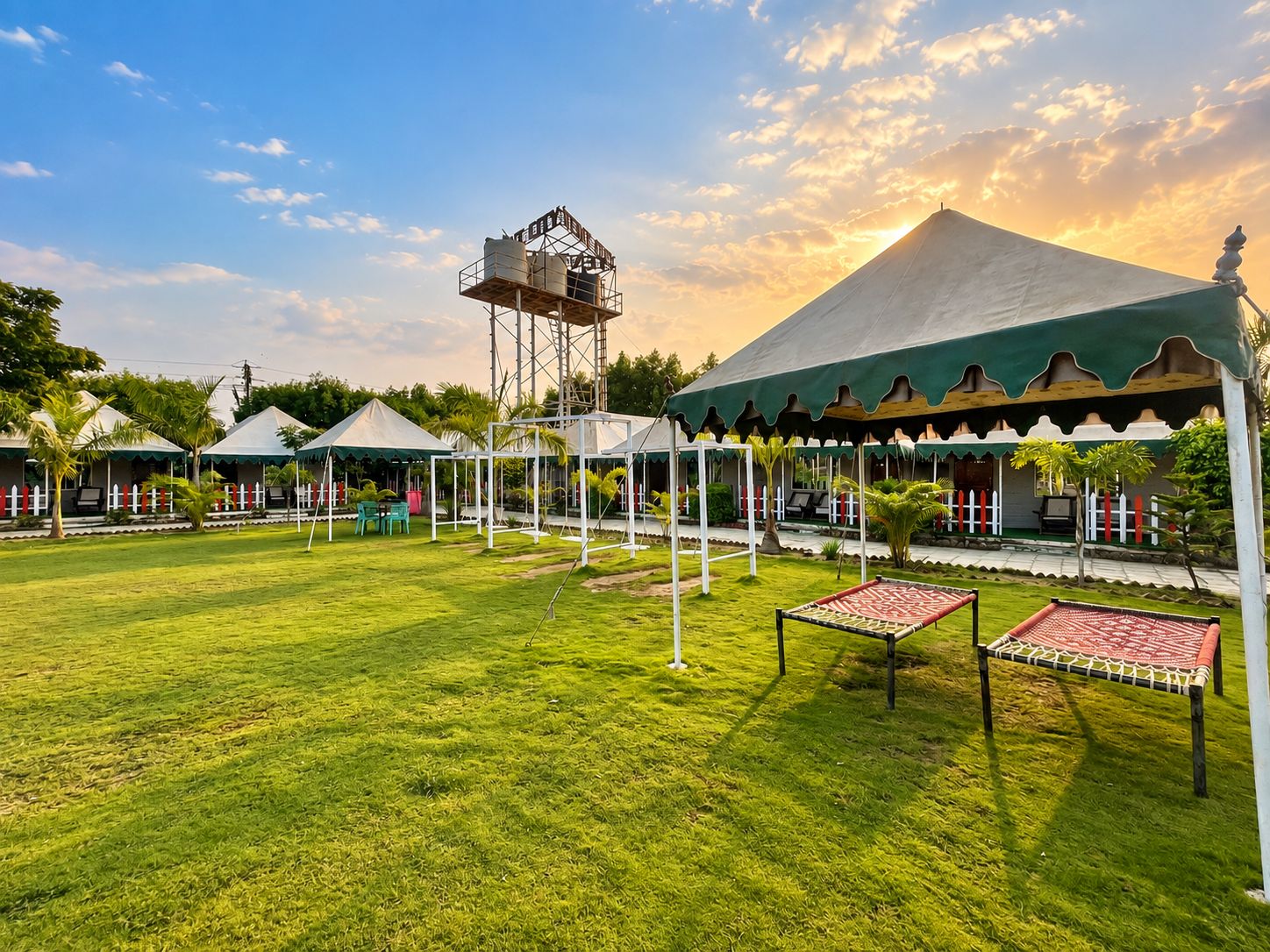 A well-maintained lawn with a gazebo, a water tower, and a large tent structure.