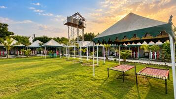 A well-maintained lawn with a gazebo, a water tower, and a large tent structure.