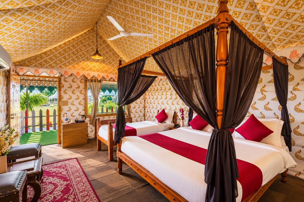 A four-poster bed with a canopy, two bedside tables, a nightstand, a red and white patterned rug, and a view of the outdoors through a window.