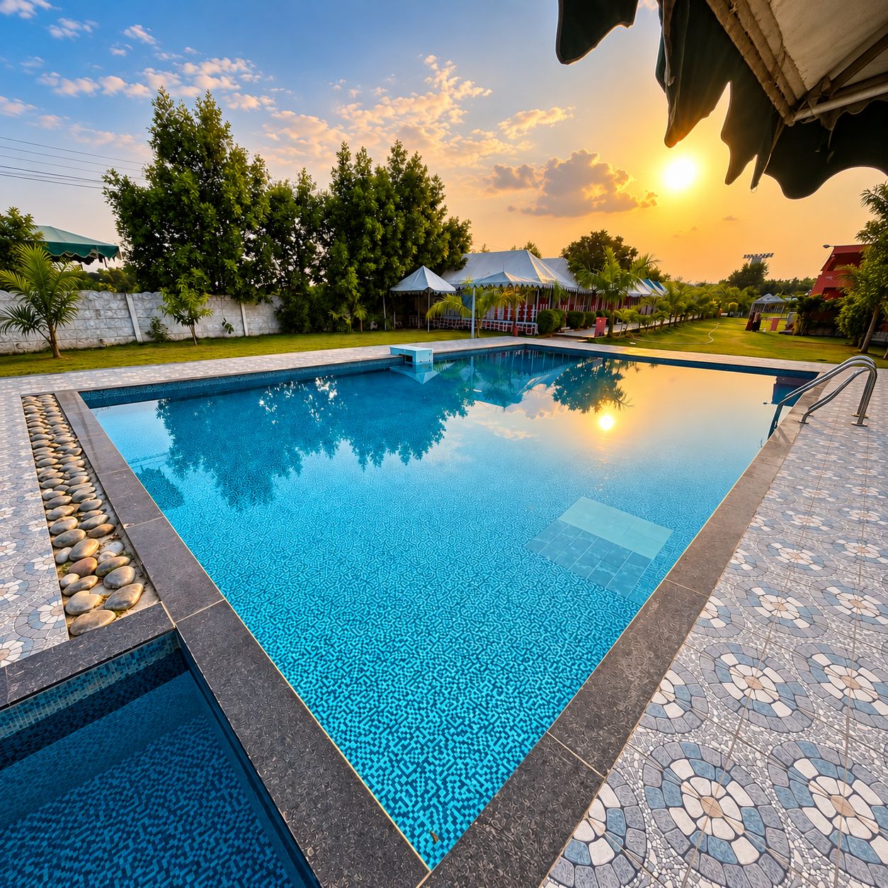 A rectangular swimming pool with a patterned tile design, surrounded by a tiled deck with a stone border.