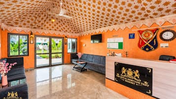 A reception area with a check-in counter, a sofa, and a desk.
