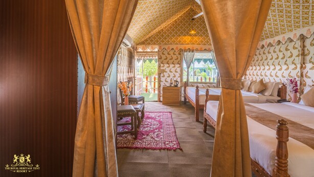 Een traditionele slaapkamer met tentstructuur, met vier bedden, een houten bank en een kamerkleed met dessin.