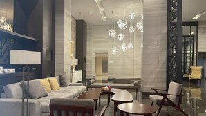 A modern hotel lobby with a sofa, chairs, a coffee table, and hanging pendant lights. - Pet Friendly Staycation at The Radiance Manila Bay (Pasay)