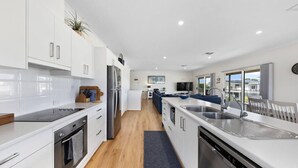 Una cocina moderna con armarios blancos, horno empotrado, lavavajillas y una isla grande con fregadero.
