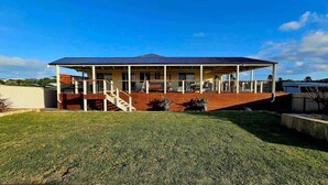 Una casa de dos pisos con un porche cubierto y una terraza de madera.
