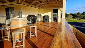 Una terraza exterior con piso de madera, una parrilla y una urna grande.