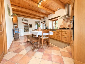 Un intérieur en bois comprenant une table et des chaises, une cuisine avec des meubles en bois et un sol carrelé.