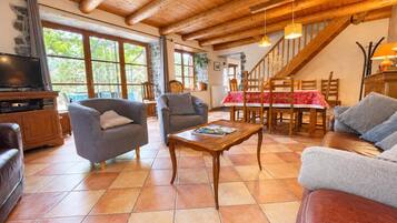 A spacious living room with a wooden ceiling, a television, and comfortable seating.