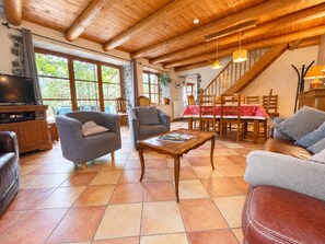 Un salon spacieux avec un plafond en bois, un téléviseur et des sièges confortables.