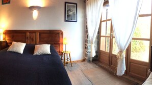Un dormitorio con una cama de madera, una mesita de noche, una lámpara y una pared de piedra.