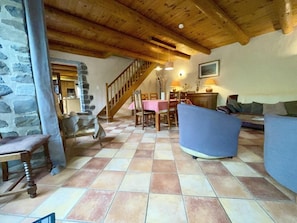 A spacious living area with a checkered floor, a staircase, a dining table, and a sofa.