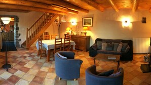 Una sala de estar acogedora con suelo a cuadros, un comedor con mesa y sillas, un sofá y una escalera que sube a otro nivel.