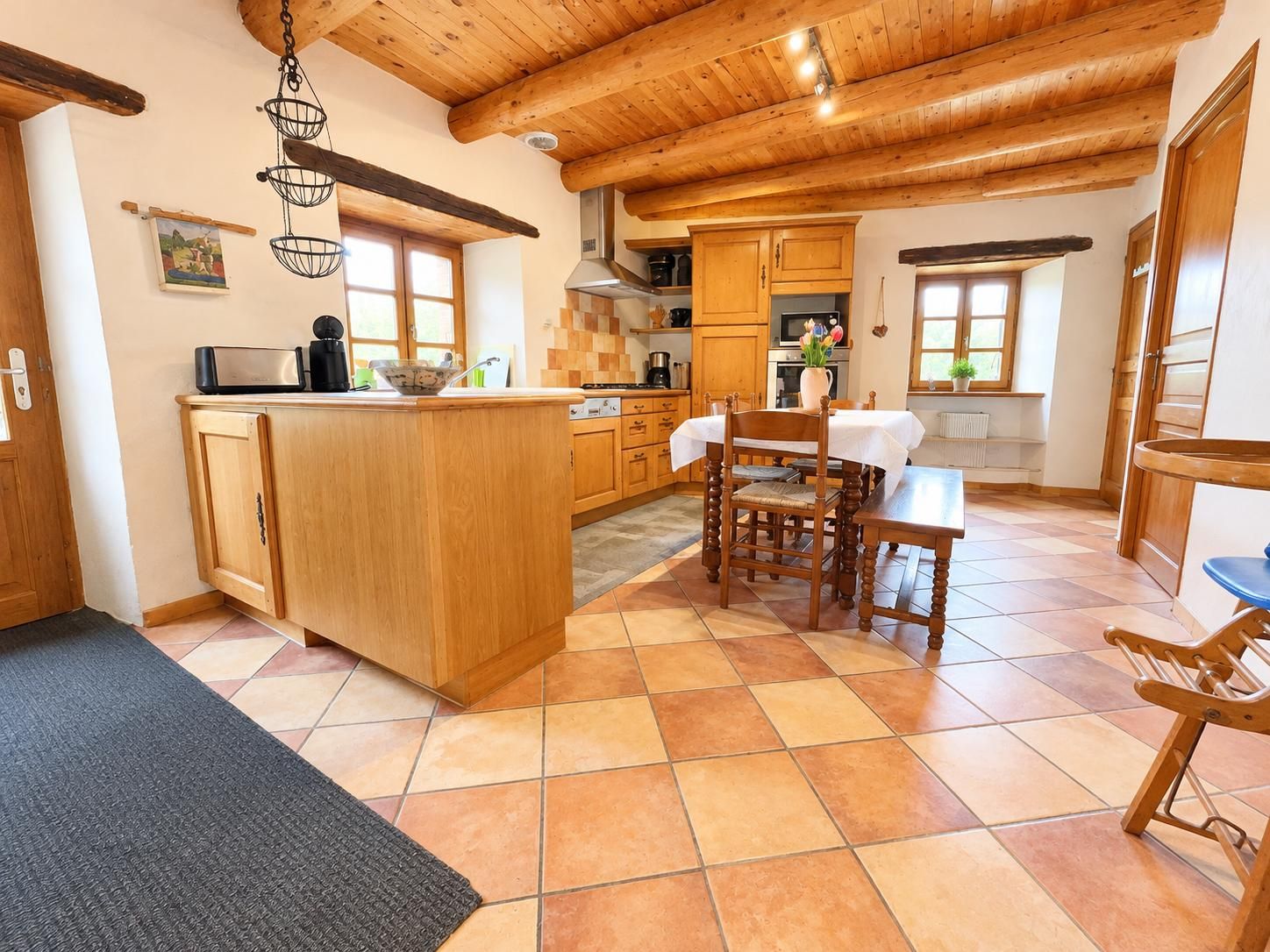 A kitchen with wooden cabinets, a central island, and a dining area with a table and chairs.
