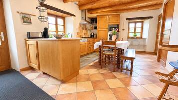 A kitchen with wooden cabinets, a central island, and a dining area with a table and chairs.