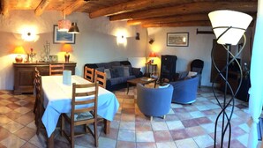 Una sala acogedora con una mesa de comedor, sillas, un sofá y una escalera.