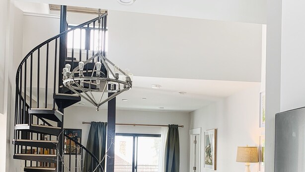 A modern kitchen with dark cabinets, a central island, and a spiral staircase. - Penthouse Cozy Condo in the heart of Downtown Winter Park (Winter Park)