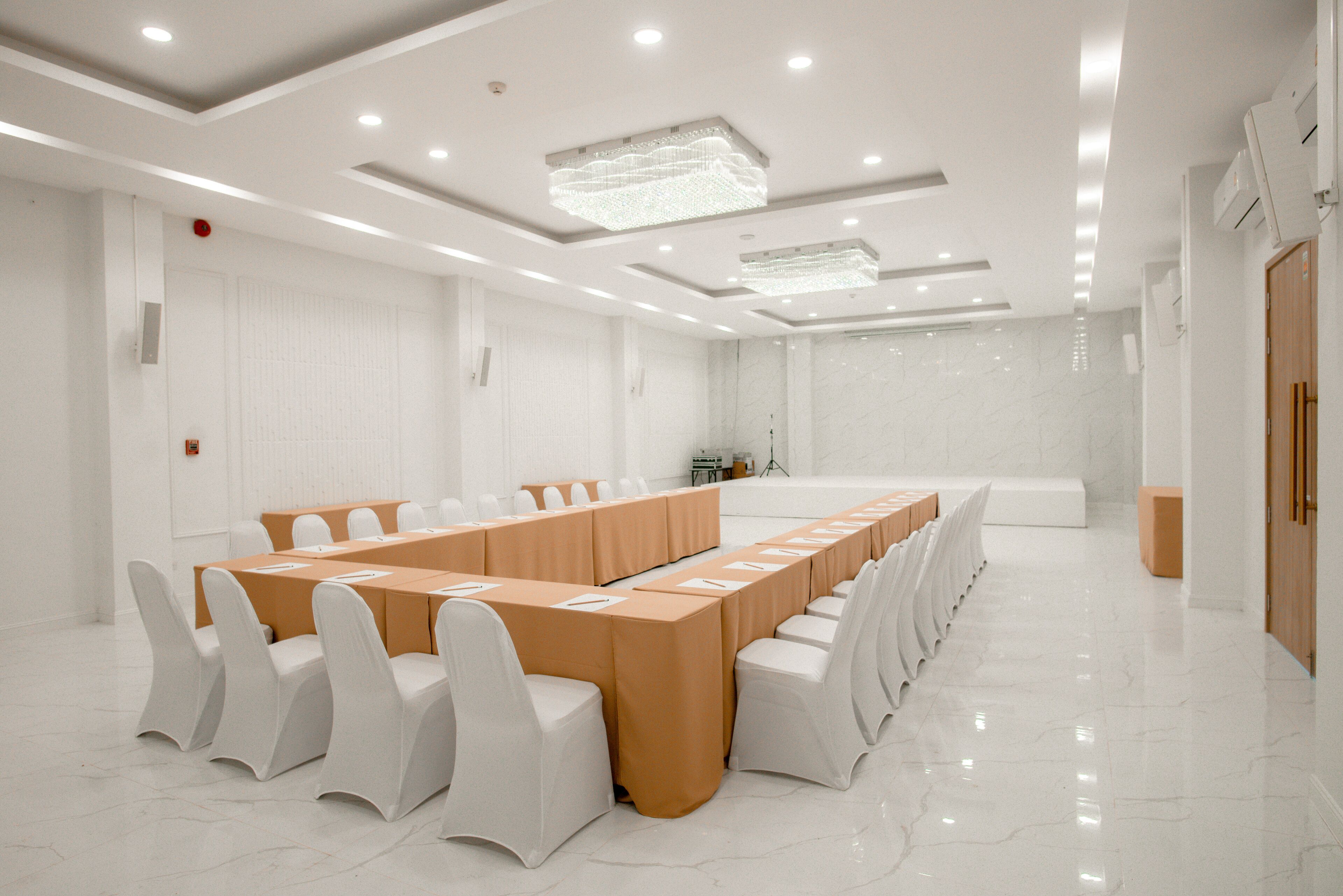 A conference room with a long table, white chairs, and a marble floor.