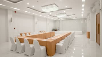 A conference room with a long table, white chairs, and a marble floor.