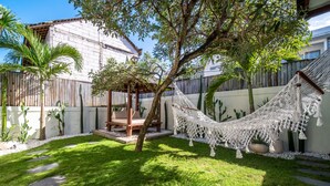 A hammock under a tree in a well-maintained garden with a wooden pergola, stone steps, and a white fence. - Cozy 3br Villa with Pool in Canggu (Canggu)