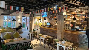 A cozy cafe with a bar area, wooden furniture, and a mural on the wall. - Lotus Club Boutique Hotel (Tarakeshwar)