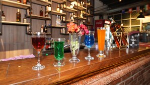 A bar with various colorful drinks and bottles on shelves in the background. - Lotus Club Boutique Hotel (Tarakeshwar)