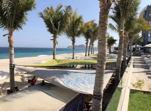 Um resort à beira-mar com palmeiras, área de piscina e vista para o oceano.