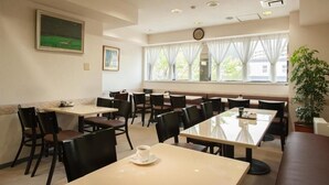 A dining area with multiple tables and chairs, a clock on the wall, and a large window with curtains. - Hotel Yassa (Mihara)